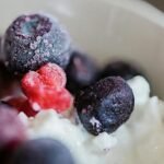 A detailed shot of frozen berries on creamy yogurt in a bowl.