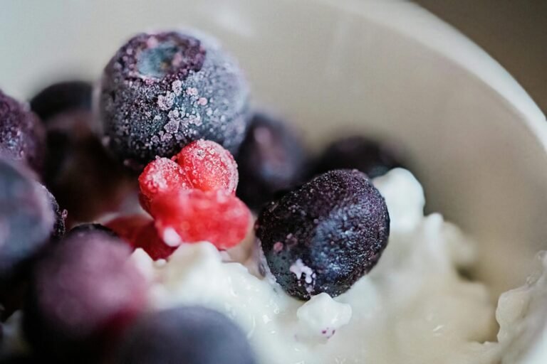 A detailed shot of frozen berries on creamy yogurt in a bowl.