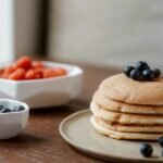 Delicious homemade stack of pancakes topped with fresh blueberries, perfect for a sweet breakfast.