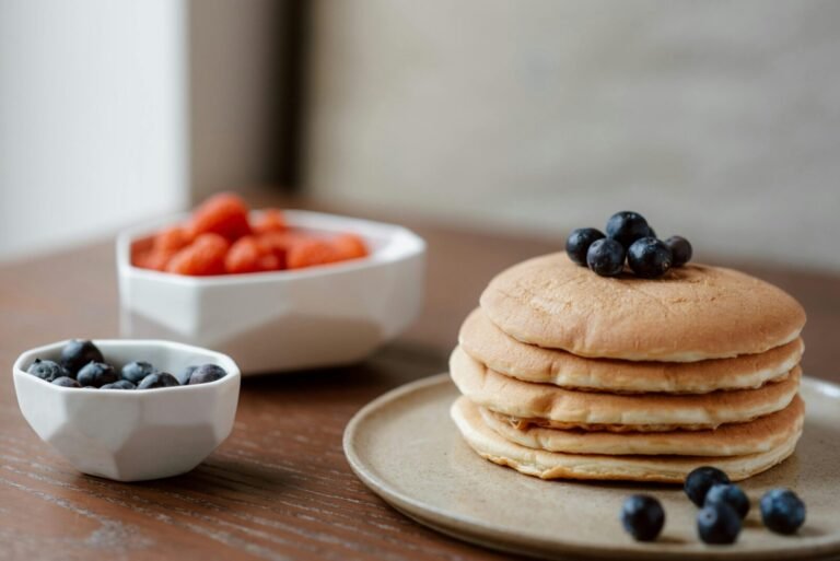 Delicious homemade stack of pancakes topped with fresh blueberries, perfect for a sweet breakfast.