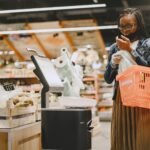 A woman shopping in a supermarket, checking items with a basket in hand.